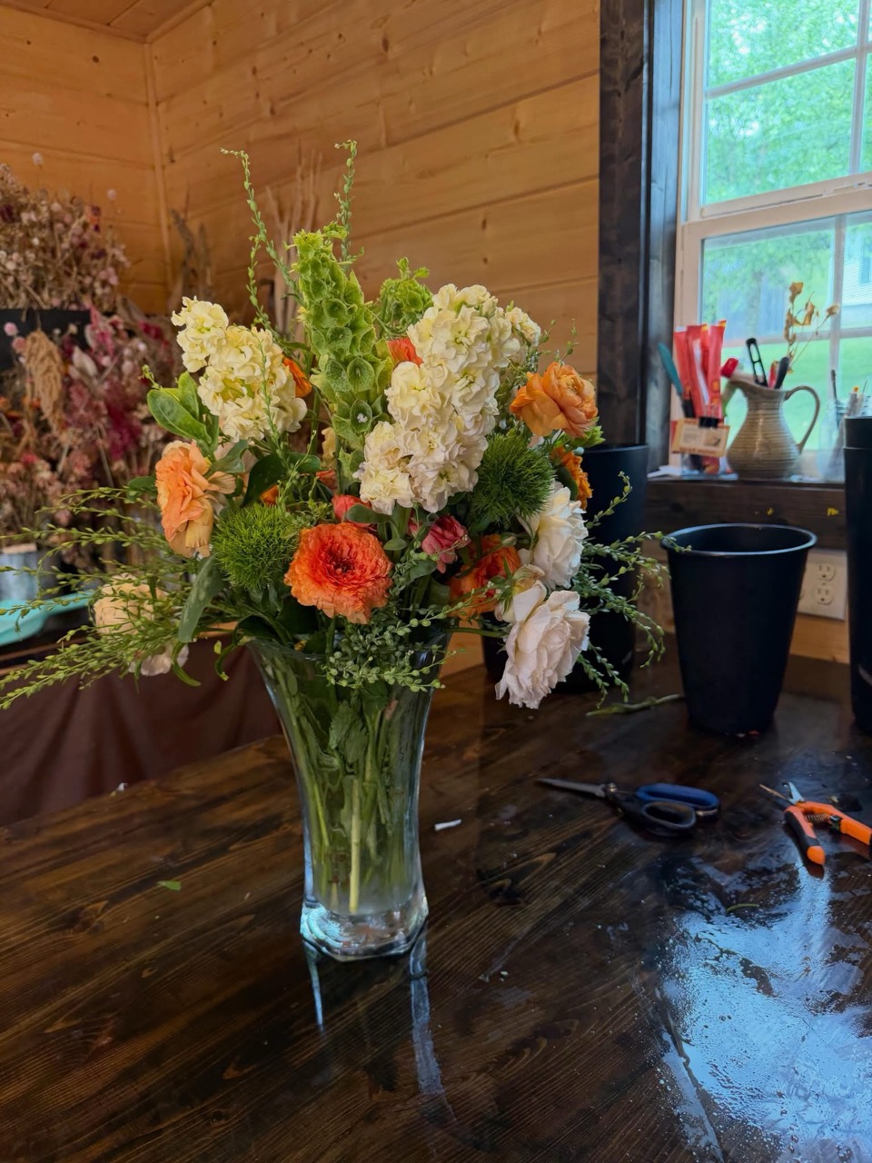 Cream, orange, and green bouquet in a glass vase